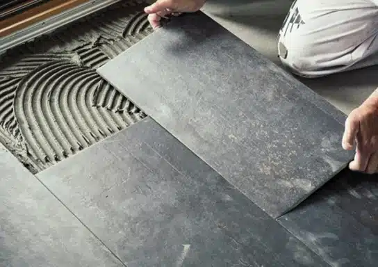 Les mains d'une personne en train du carrelage