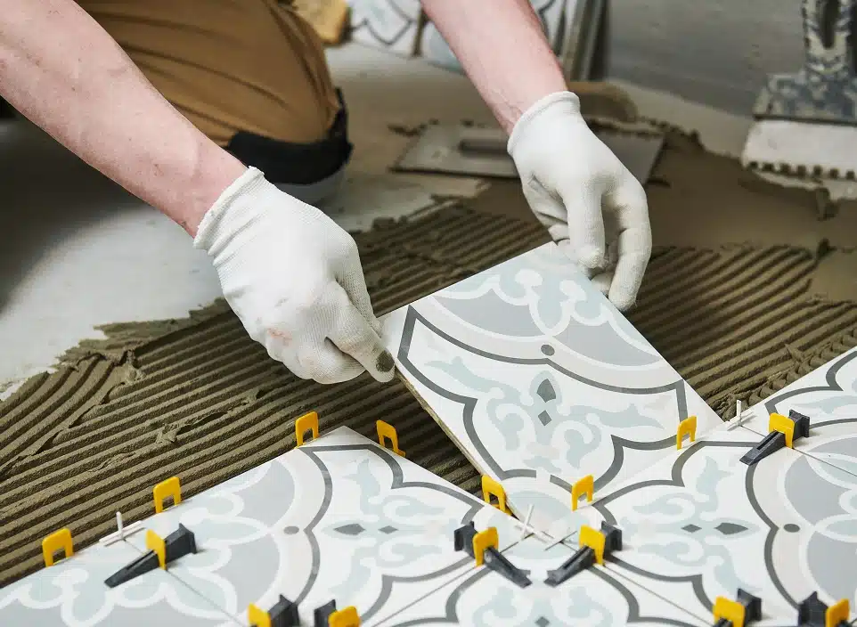 Les mains d'une personne en train de poser des carreaux ciment au sol