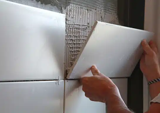 Les mains d'une personne en train de poser une faillance dans une salle de bain